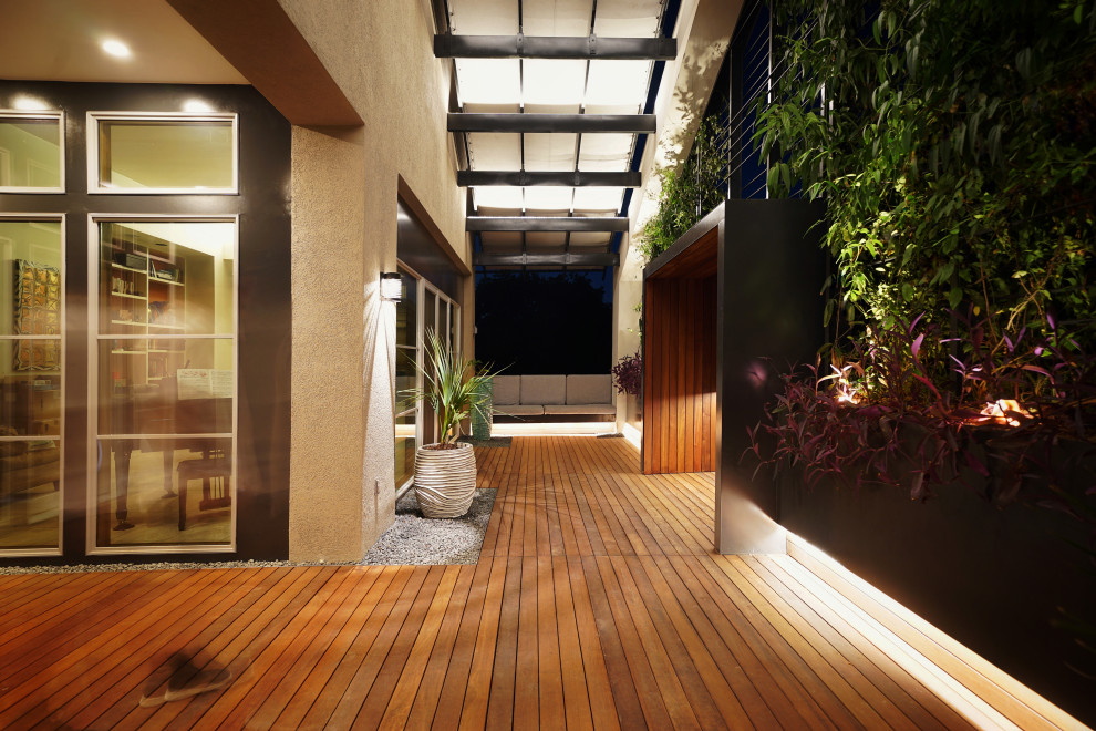 Imagen de patio moderno pequeño en patio delantero con jardín vertical, entablado y toldo