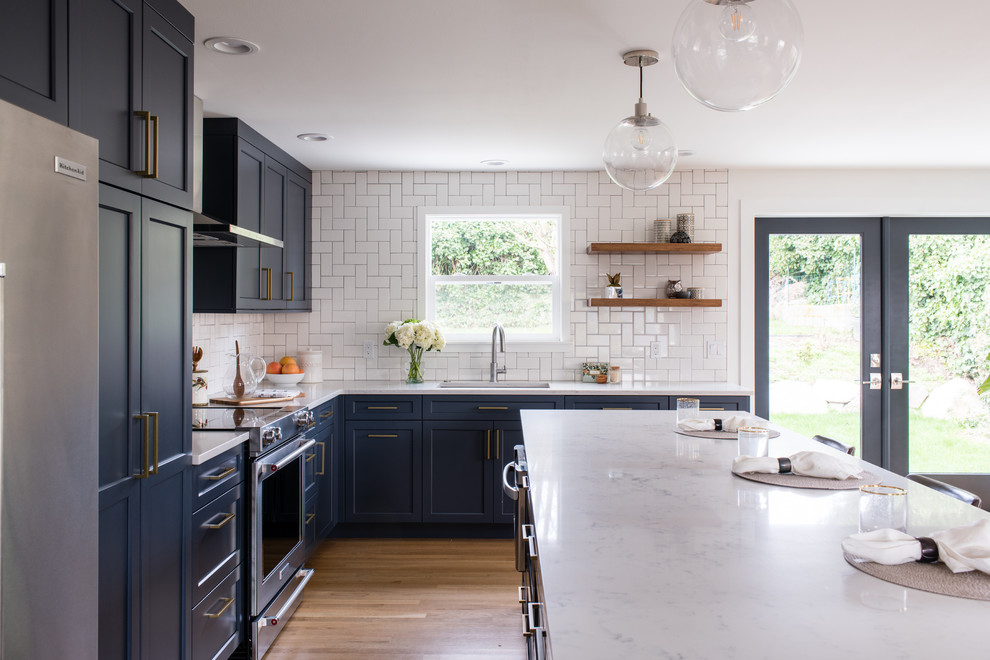 Inspiration for a mid-sized transitional l-shaped eat-in kitchen in Seattle with a drop-in sink, shaker cabinets, blue cabinets, quartz benchtops, white splashback, stainless steel appliances, dark hardwood floors, with island, brown floor, white benchtop and subway tile splashback.