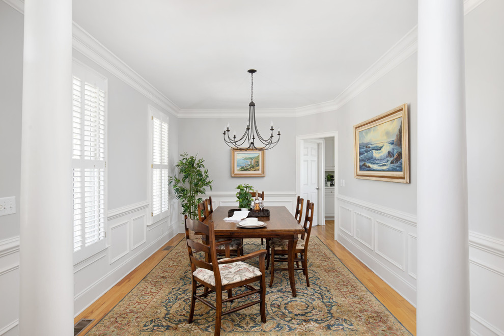 This is an example of a traditional separate dining room in Charleston with white walls, medium hardwood floors, no fireplace and brown floor.