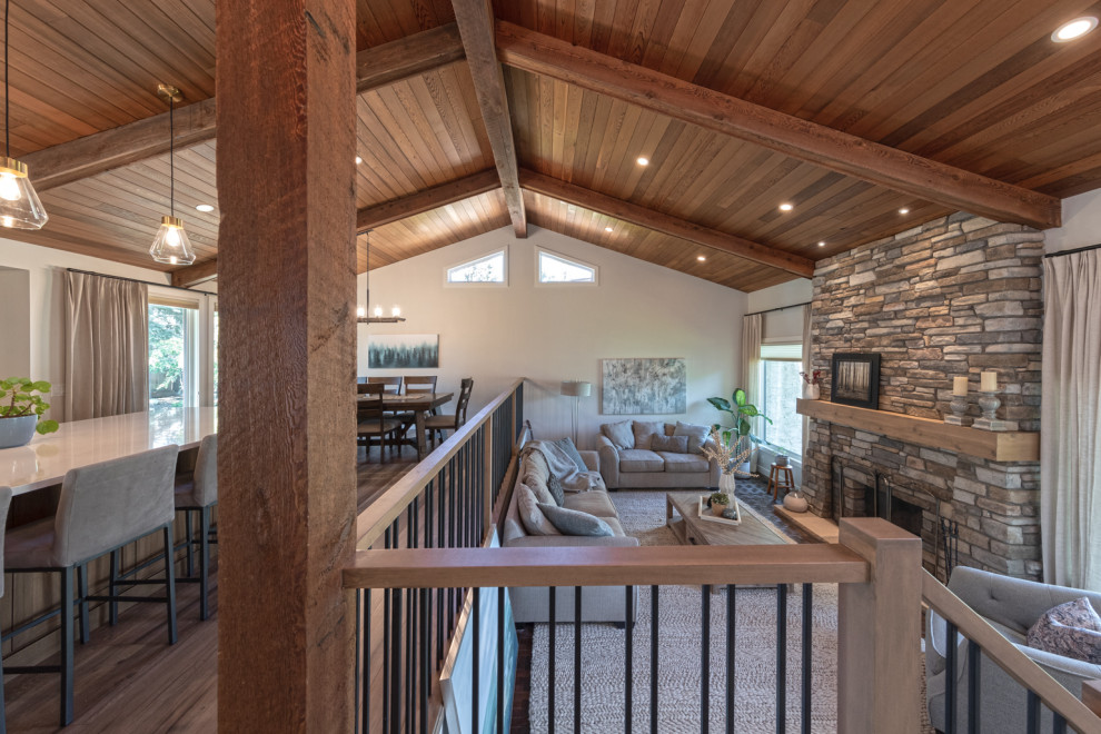 Medium sized country mezzanine living room in Edmonton with white walls, light hardwood flooring, a standard fireplace, a stacked stone fireplace surround, brown floors and exposed beams.