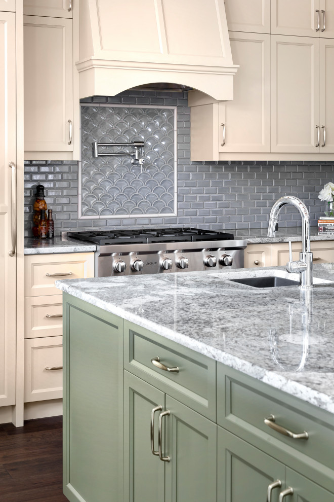 Example of a large transitional l-shaped dark wood floor, brown floor and exposed beam eat-in kitchen design with a single-bowl sink, shaker cabinets, beige cabinets, granite countertops, blue backsplash, glass tile backsplash, paneled appliances, an island and multicolored countertops