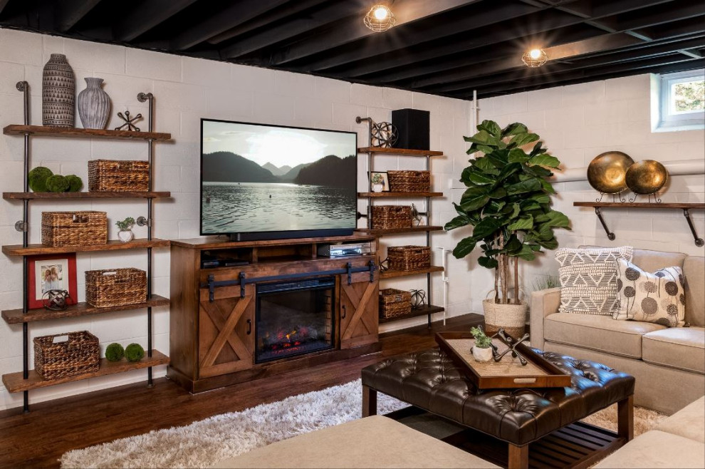 This is an example of a medium sized urban fully buried basement in Philadelphia with white walls, laminate floors, a standard fireplace, a wooden fireplace surround, brown floors and exposed beams.