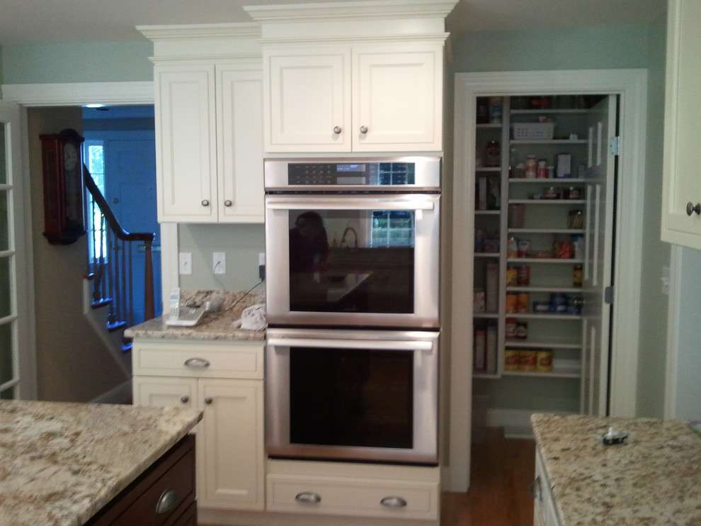 Transitional u-shaped light wood floor eat-in kitchen photo in Boston with an undermount sink, shaker cabinets, white cabinets, quartz countertops, beige backsplash, stainless steel appliances and an island