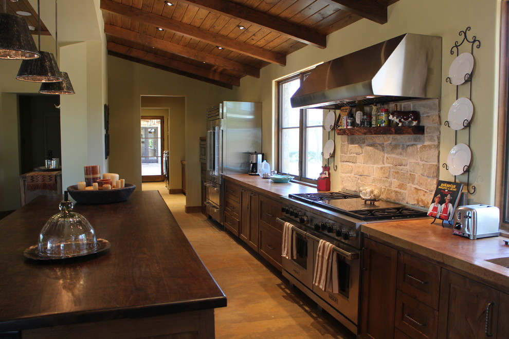 This is an example of a large galley kitchen in Other with shaker cabinets, dark wood cabinets, concrete benchtops, limestone splashback, stainless steel appliances, concrete floors, with island and brown benchtop.