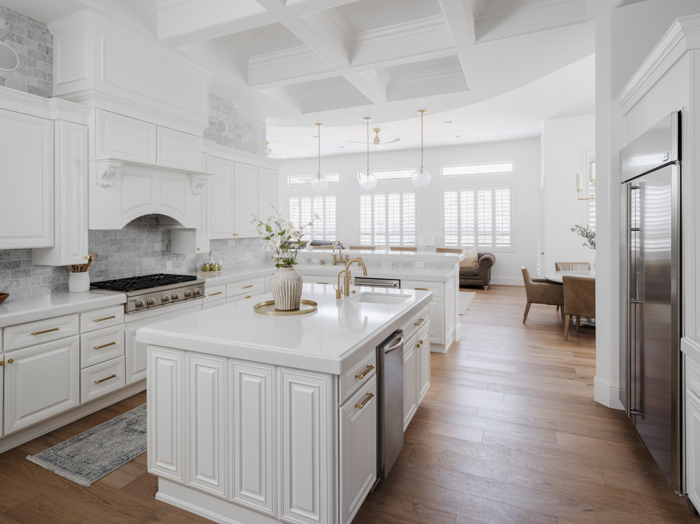 Idéer för att renovera ett stort vintage vit vitt kök, med en undermonterad diskho, luckor med upphöjd panel, vita skåp, bänkskiva i kvarts, vitt stänkskydd, stänkskydd i marmor, rostfria vitvaror, ljust trägolv, en köksö och beiget golv