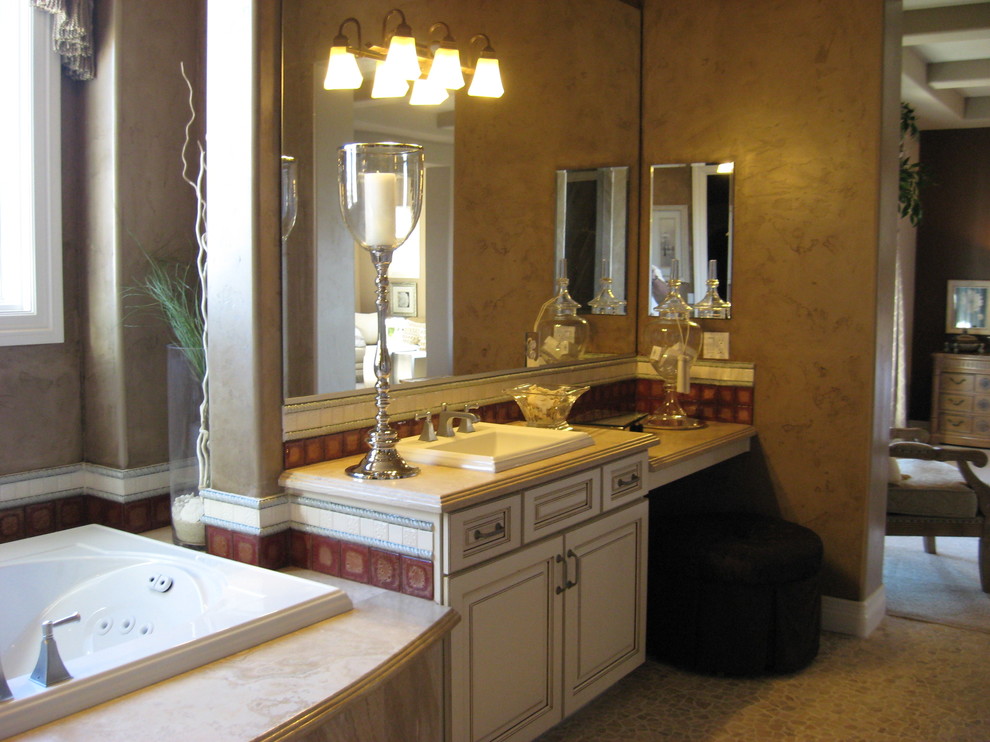 Inspiration for a large traditional master bathroom in Las Vegas with a drop-in sink, furniture-like cabinets, white cabinets, marble benchtops, a drop-in tub, a corner shower, a two-piece toilet, beige tile, stone tile, brown walls and pebble tile floors.