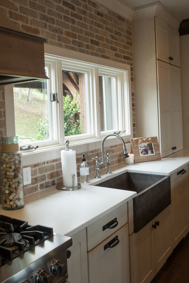 Open concept kitchen - large transitional galley dark wood floor and brown floor open concept kitchen idea with a farmhouse sink, shaker cabinets, quartz countertops, brown backsplash, brick backsplash, stainless steel appliances and an island
