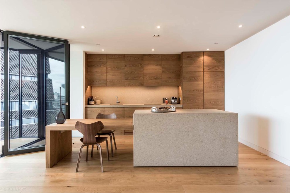 This is an example of a contemporary kitchen in London with a single-bowl sink, flat-panel cabinets, medium wood cabinets, beige splashback, light hardwood floors and multiple islands.