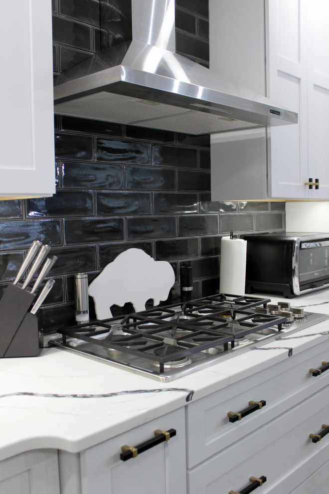 Example of a large transitional single-wall vinyl floor and beige floor eat-in kitchen design with a farmhouse sink, shaker cabinets, white cabinets, quartz countertops, black backsplash, subway tile backsplash, stainless steel appliances, an island and white countertops