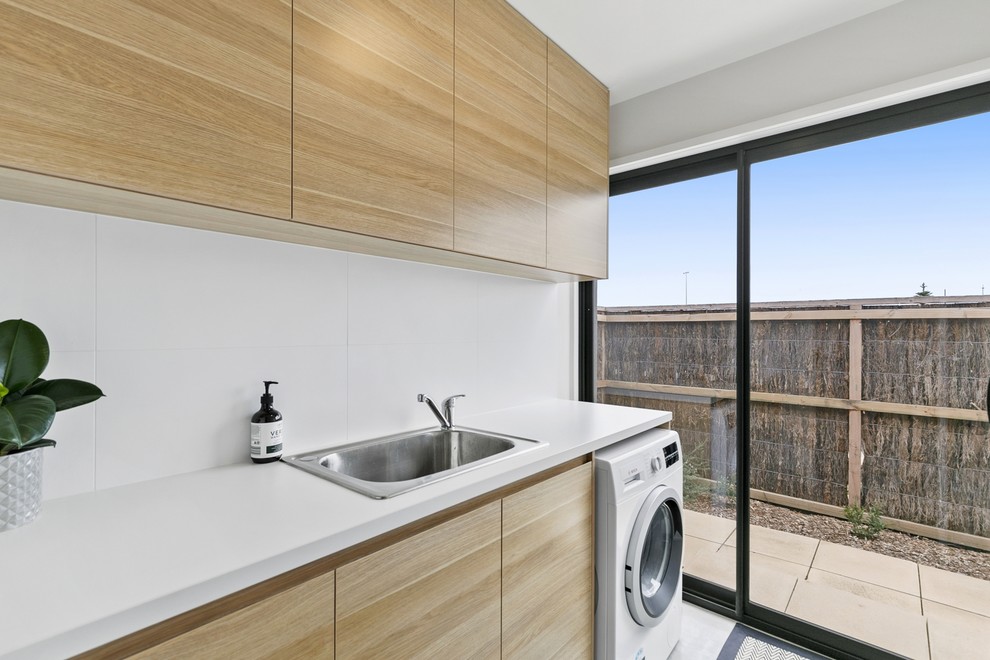 Design ideas for a small galley dedicated laundry room in Geelong with a drop-in sink, flat-panel cabinets, laminate benchtops, white walls, concrete floors, an integrated washer and dryer and white benchtop.