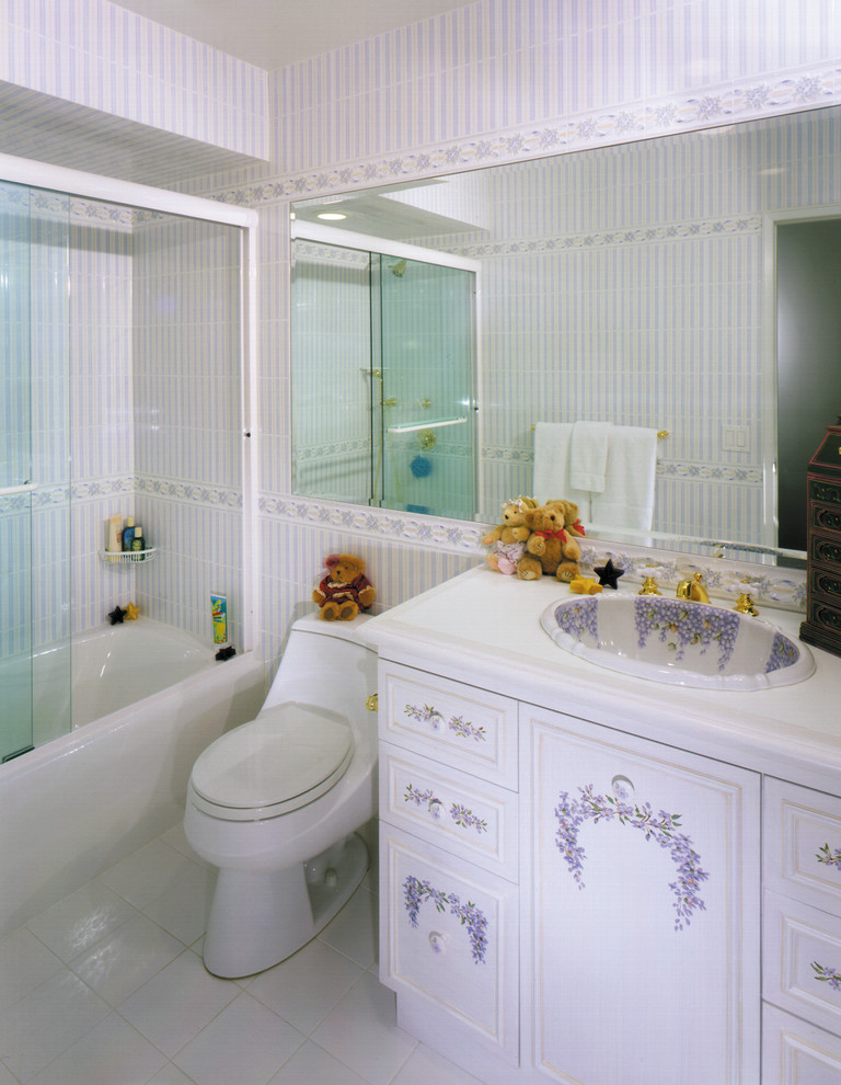 This is an example of a mid-sized transitional kids bathroom in New York with a drop-in sink, furniture-like cabinets, distressed cabinets, engineered quartz benchtops, an alcove tub, a one-piece toilet, white tile, ceramic tile and ceramic floors.