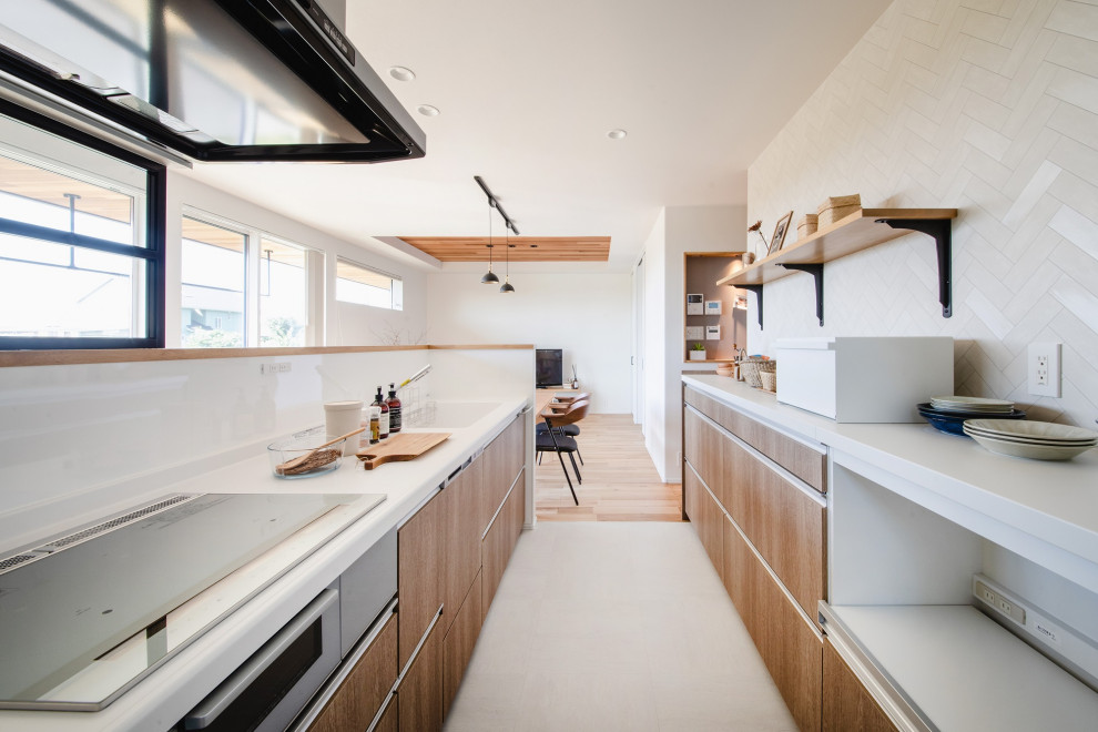 На фото: прямая кухня-гостиная в восточном стиле с серым фартуком, белой столешницей и мойкой у окна