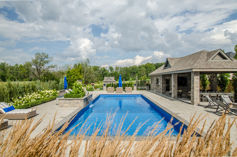 Large traditional backyard pool in Toronto with brick pavers.