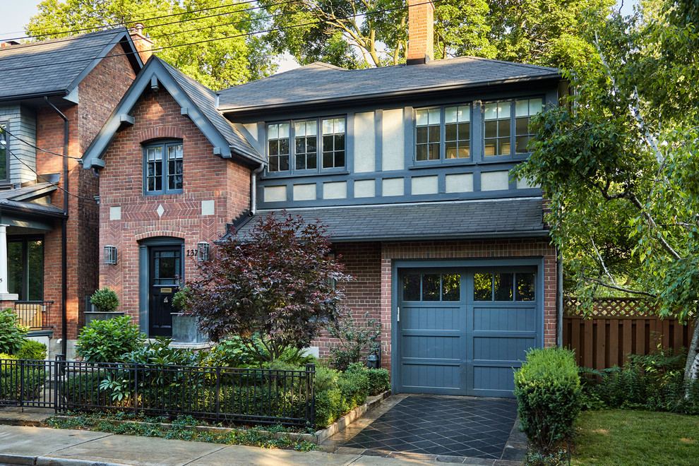 Photo of a small traditional two-storey brick red house exterior in Toronto with a gable roof and a shingle roof.
