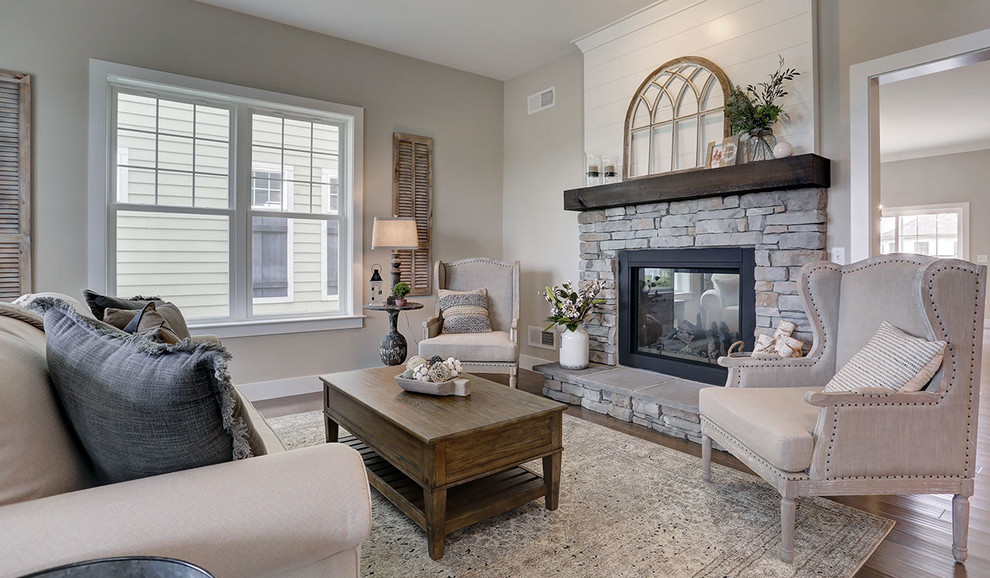 Design ideas for a mid-sized country open concept family room in Other with grey walls, dark hardwood floors, a two-sided fireplace and a stone fireplace surround.