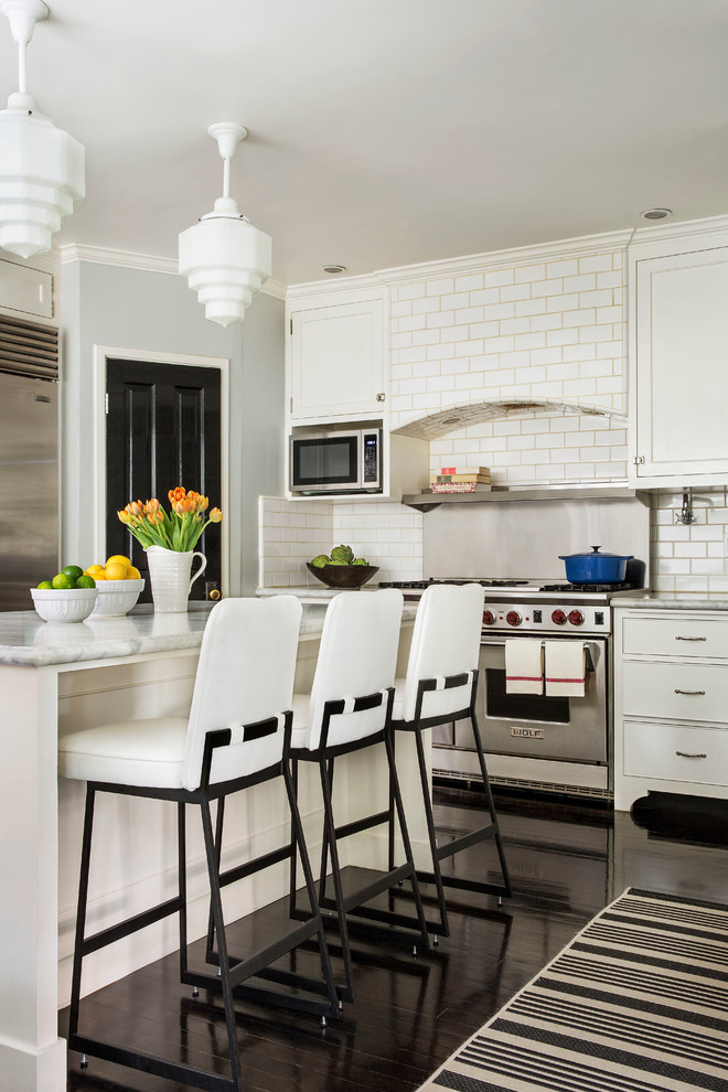 This is an example of a transitional kitchen in Los Angeles with marble benchtops, white splashback, subway tile splashback, stainless steel appliances, with island and dark hardwood floors.