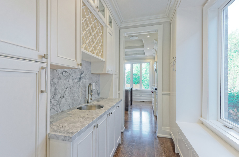 Inspiration for a large transitional single-wall medium tone wood floor kitchen pantry remodel in Toronto with a single-bowl sink, flat-panel cabinets, white cabinets, marble countertops, gray backsplash, stone tile backsplash, stainless steel appliances and an island