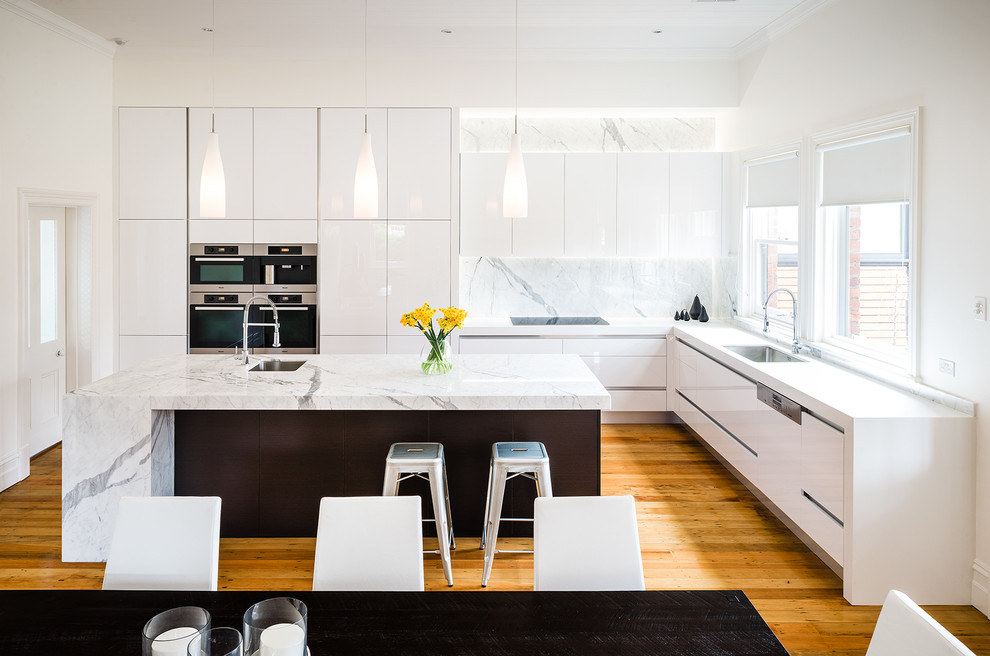 Design ideas for an expansive contemporary l-shaped eat-in kitchen in Melbourne with an undermount sink, flat-panel cabinets, white cabinets, marble benchtops, with island, white splashback, stainless steel appliances, medium hardwood floors and marble splashback.