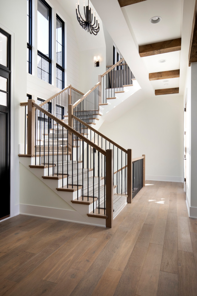 Large transitional wood u-shaped staircase in Minneapolis with planked wall panelling, wood risers and mixed railing.