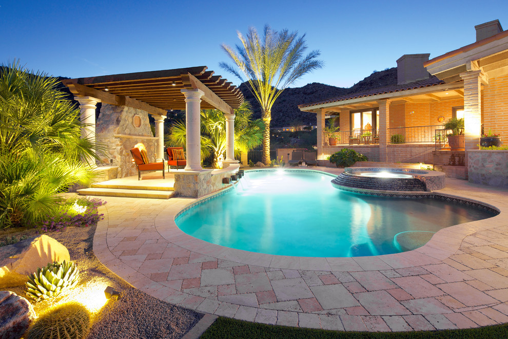Design ideas for a large mediterranean backyard custom-shaped natural pool in Phoenix with a pool house and natural stone pavers.