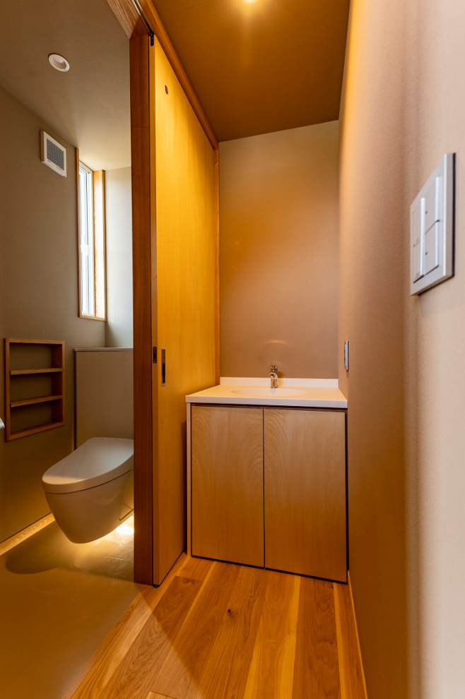 Exemple d'un WC suspendu de taille moyenne avec un placard à porte plane, des portes de placard blanches, un carrelage beige, un mur beige, un sol en bois brun, un lavabo encastré, un sol beige et meuble-lavabo encastré.