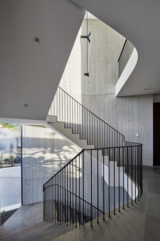 This is an example of a large contemporary concrete curved staircase in Perth with tile risers and metal railing.