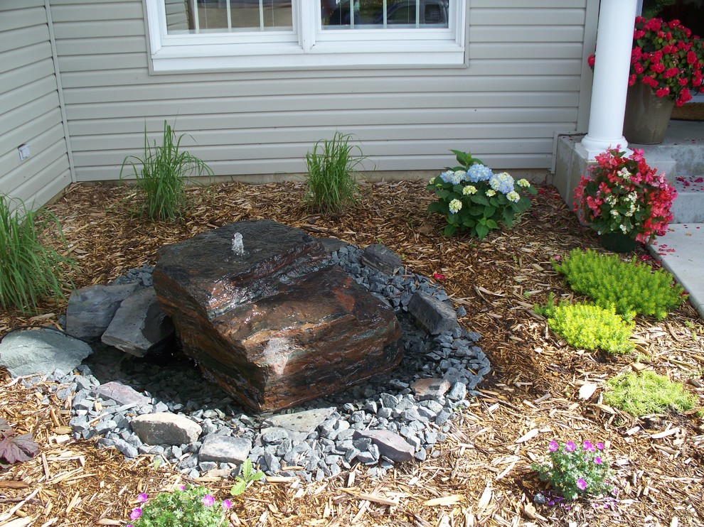 This is an example of a small rustic partial sun front yard water fountain landscape for summer.