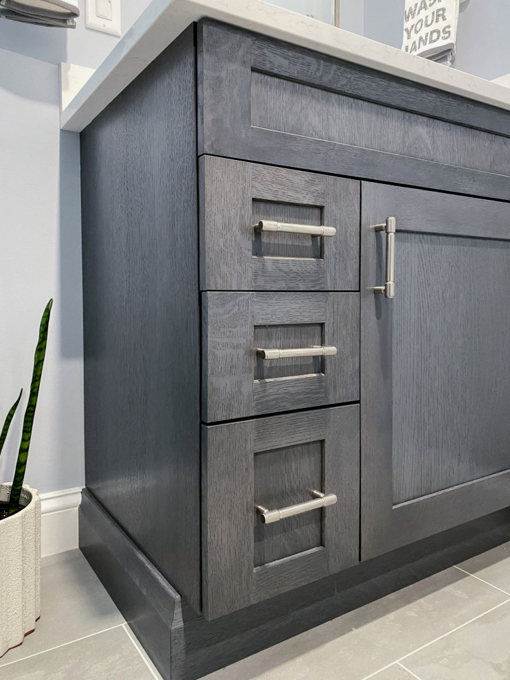 Corner shower - transitional white tile and ceramic tile porcelain tile, gray floor and single-sink corner shower idea in Boston with shaker cabinets, gray cabinets, a one-piece toilet, gray walls, an undermount sink, quartz countertops, a hinged shower door, white countertops and a built-in vanity