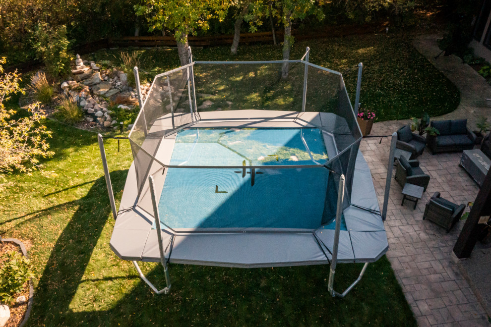 This is an example of a large modern partial sun backyard outdoor basketball/tennis/multi-game court for summer.