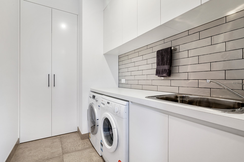 Photo of a mid-sized contemporary galley utility room in Melbourne with a drop-in sink, laminate benchtops, white walls and porcelain floors.