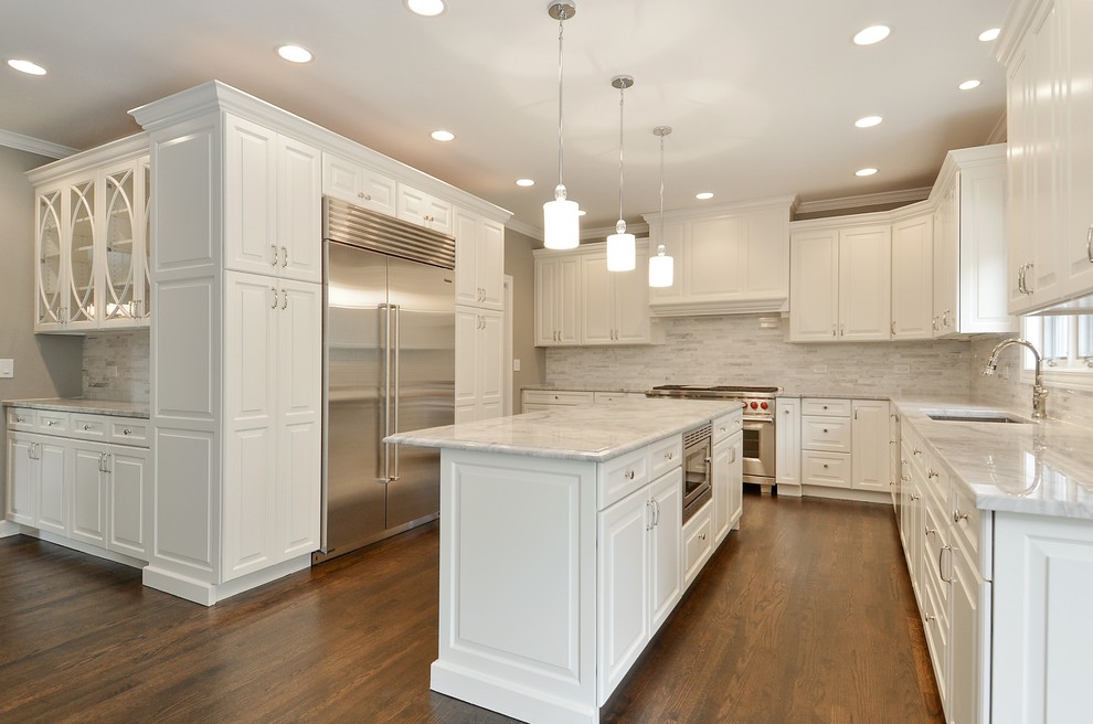 Example of a transitional dark wood floor eat-in kitchen design in Chicago with an island, a drop-in sink, raised-panel cabinets, white cabinets, marble countertops, gray backsplash, ceramic backsplash and stainless steel appliances