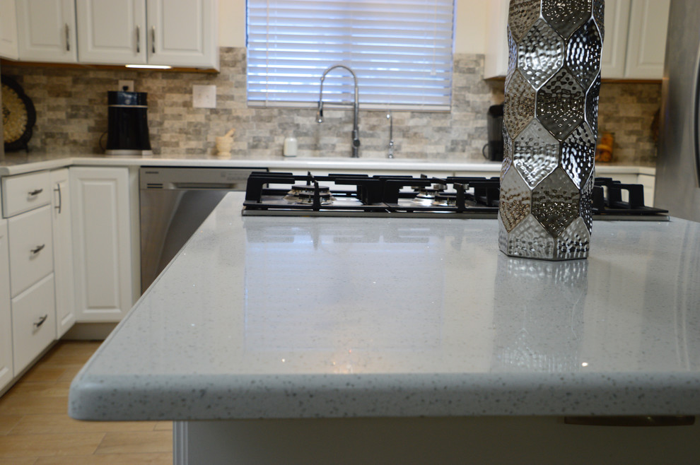 Enclosed kitchen - mid-sized transitional l-shaped porcelain tile enclosed kitchen idea in Albuquerque with an undermount sink, raised-panel cabinets, white cabinets, quartz countertops, beige backsplash, porcelain backsplash, stainless steel appliances and no island