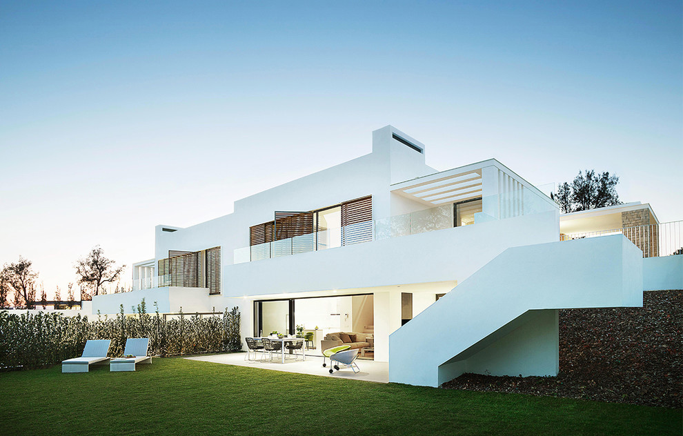 Photo of a mid-sized contemporary three-storey stucco white exterior in Barcelona with a flat roof.