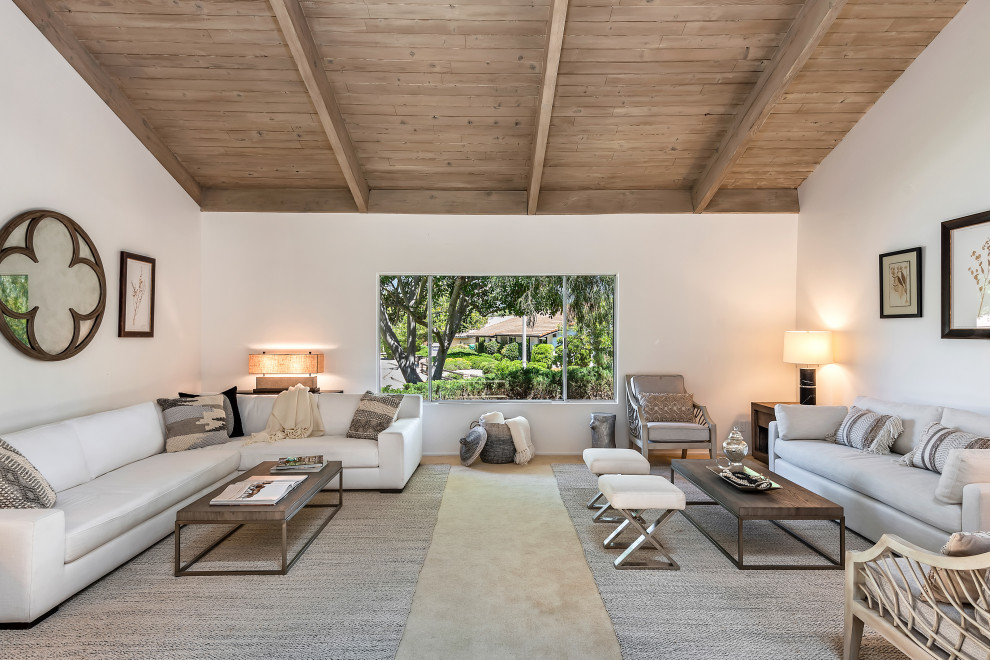 This is an example of a contemporary living room in Santa Barbara with white walls, exposed beam, vaulted and wood.