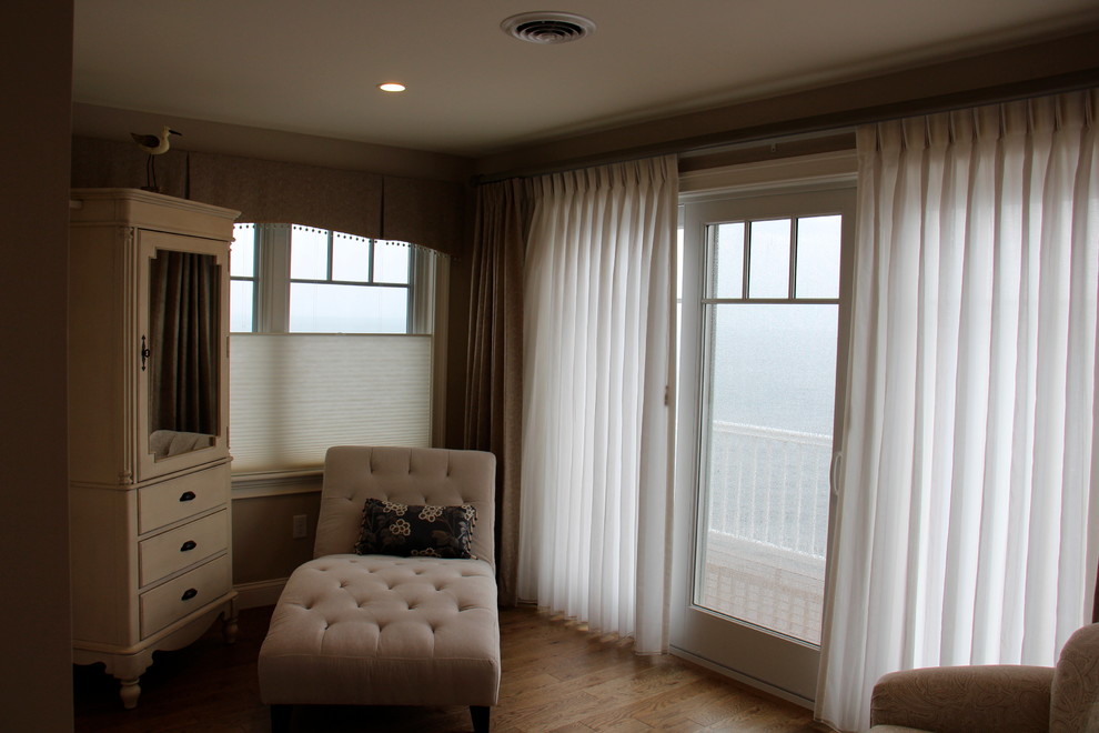 Photo of a mid-sized transitional master bedroom in Portland Maine with beige walls and light hardwood floors.