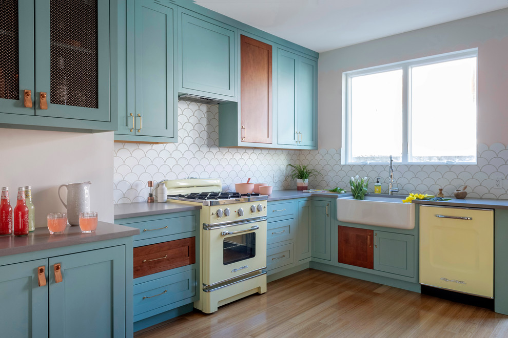 Design ideas for a mid-sized eclectic l-shaped kitchen in Philadelphia with a farmhouse sink, turquoise cabinets, quartz benchtops, white splashback, ceramic splashback, coloured appliances, bamboo floors, no island, grey benchtop, shaker cabinets and brown floor.