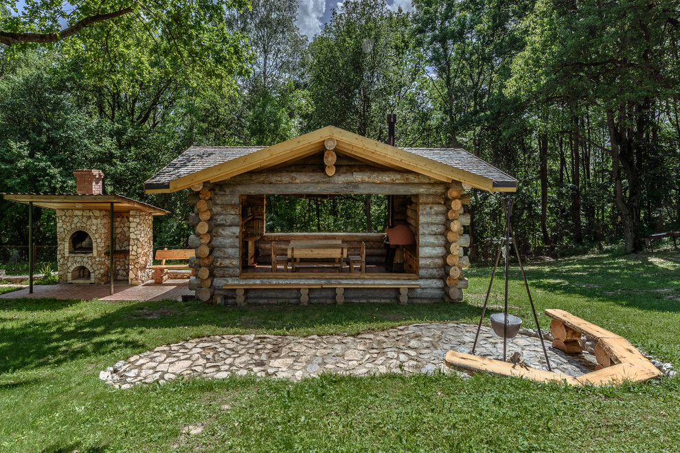 This is an example of a country backyard patio in Moscow with an outdoor kitchen, natural stone pavers and a gazebo/cabana.