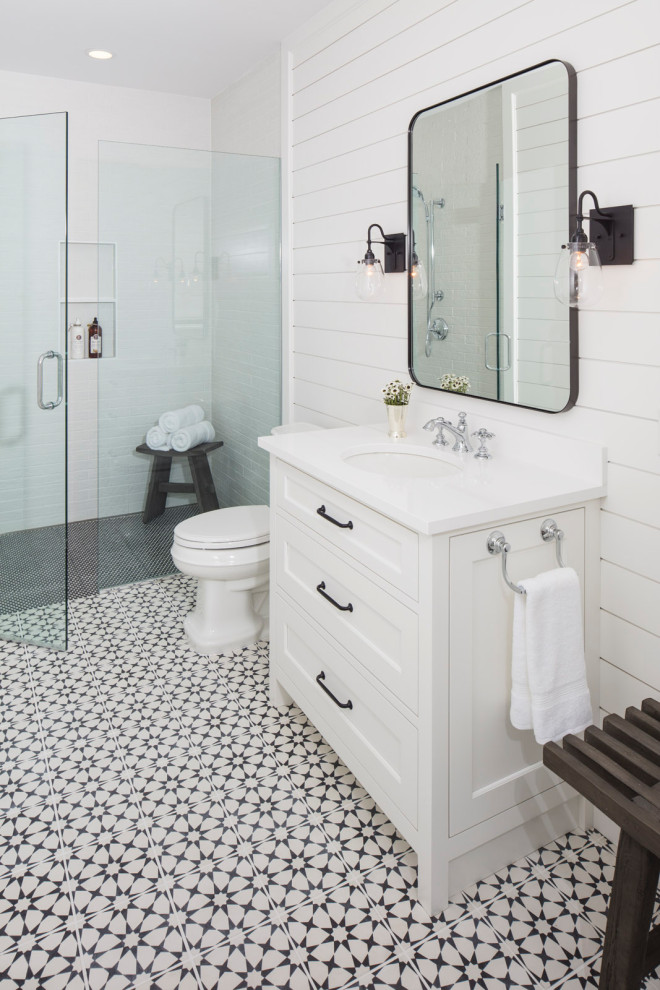 Design ideas for a mid-sized transitional 3/4 bathroom in Minneapolis with recessed-panel cabinets, white cabinets, a curbless shower, a one-piece toilet, white tile, white walls, cement tiles, an undermount sink, engineered quartz benchtops, white floor, a hinged shower door and white benchtops.