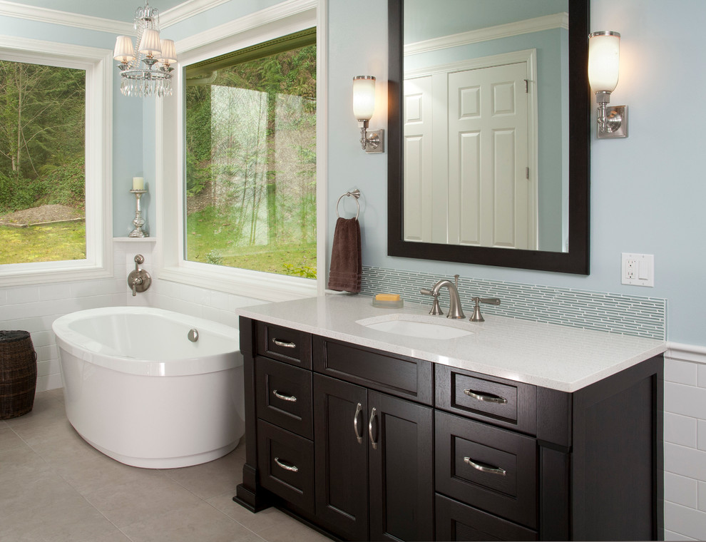 This is an example of a large traditional master bathroom in Seattle with an undermount sink, recessed-panel cabinets, dark wood cabinets, a freestanding tub, blue tile, glass tile, blue walls, ceramic floors and quartzite benchtops.