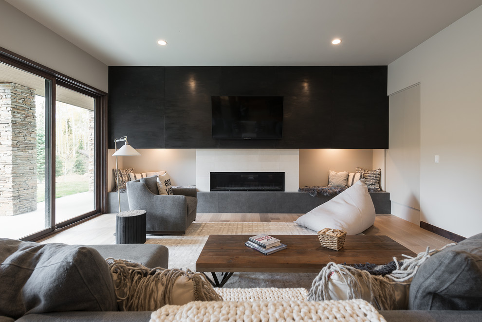 Inspiration for a contemporary family room in Salt Lake City with white walls, light hardwood floors, a ribbon fireplace and a wall-mounted tv.