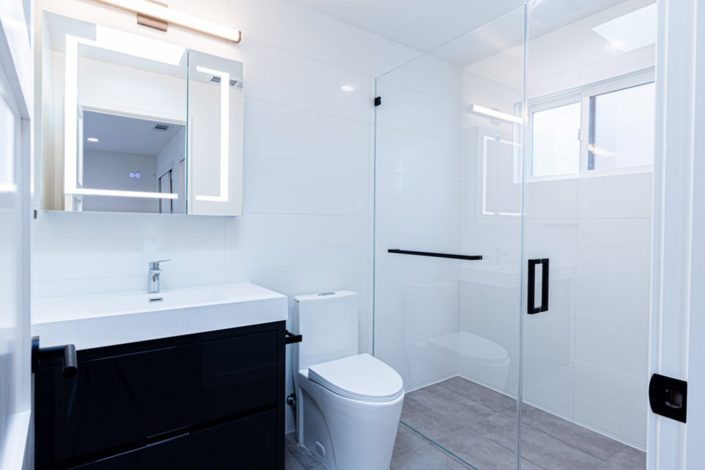 Réalisation d'une salle d'eau minimaliste avec des portes de placard noires, une douche à l'italienne, un carrelage blanc, des carreaux de céramique, un mur blanc, un sol en carrelage de céramique, un lavabo encastré, un plan de toilette en marbre, un sol gris, une cabine de douche à porte battante, un plan de toilette blanc, meuble simple vasque et meuble-lavabo encastré.