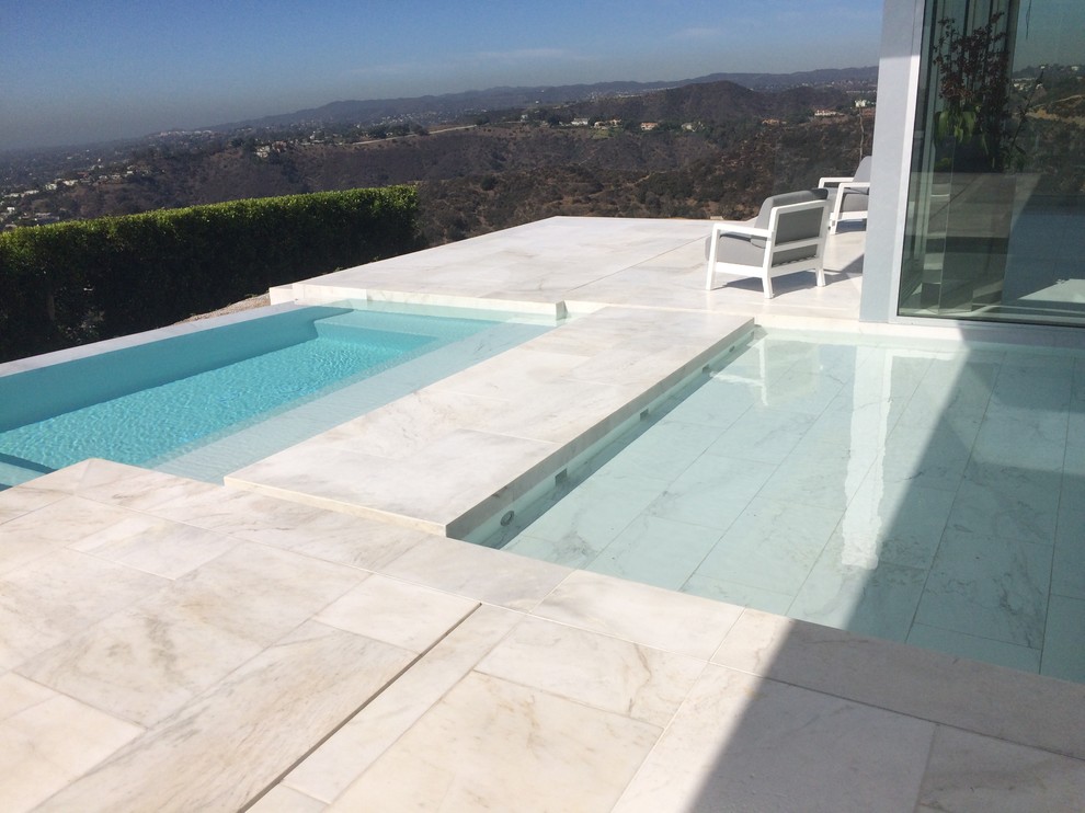 Inspiration for an expansive modern backyard l-shaped infinity pool in Los Angeles with tile.