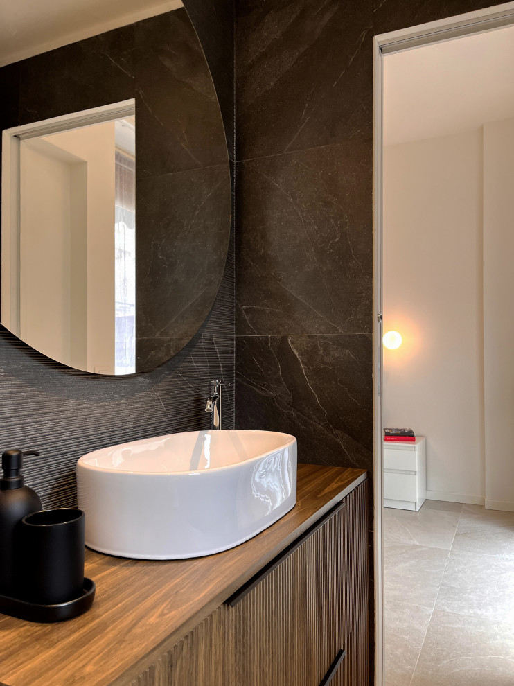 Exempel på ett litet modernt brun brunt badrum, med luckor med upphöjd panel, en kantlös dusch, en toalettstol med separat cisternkåpa, svart kakel, porslinskakel, svarta väggar, klinkergolv i porslin, ett fristående handfat, träbänkskiva, beiget golv och dusch med skjutdörr