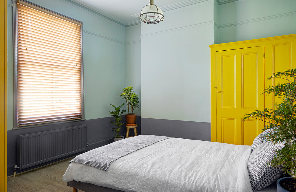 Contemporary bedroom in London with blue walls, medium hardwood floors and brown floor.