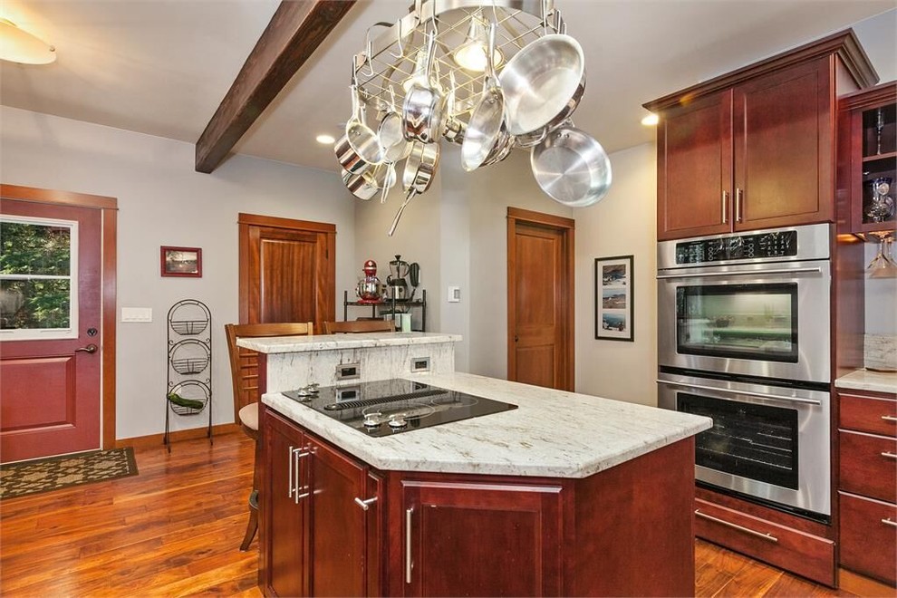 Inspiration for a large u-shaped medium tone wood floor kitchen pantry remodel in Seattle with a drop-in sink, raised-panel cabinets, dark wood cabinets, white backsplash, stainless steel appliances and an island