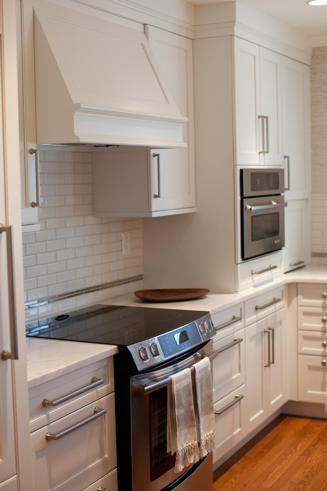 Photo of a transitional l-shaped eat-in kitchen in Baltimore with a farmhouse sink, recessed-panel cabinets, dark wood cabinets, marble benchtops, white splashback, subway tile splashback and stainless steel appliances.