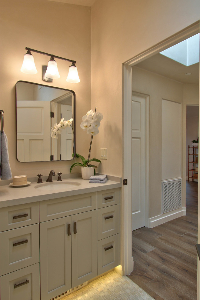 Design ideas for a mid-sized transitional master bathroom in Other with beige walls, an undermount sink, beige floor, shaker cabinets, white cabinets, a drop-in tub, a corner shower, beige tile, marble, porcelain floors, solid surface benchtops and a hinged shower door.