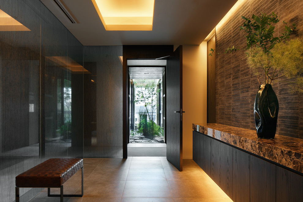 This is an example of a midcentury entryway in Tokyo with grey walls, a single front door, a dark wood front door and beige floor.