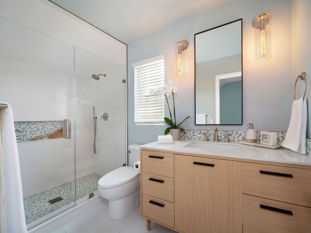 На фото: маленькая главная ванная комната в стиле ретро с плоскими фасадами, светлыми деревянными фасадами, душем в нише, унитазом-моноблоком, белой плиткой, керамогранитной плиткой, зелеными стенами, полом из керамогранита, врезной раковиной, столешницей из искусственного кварца, белым полом, душем с распашными дверями, белой столешницей, тумбой под одну раковину и встроенной тумбой для на участке и в саду