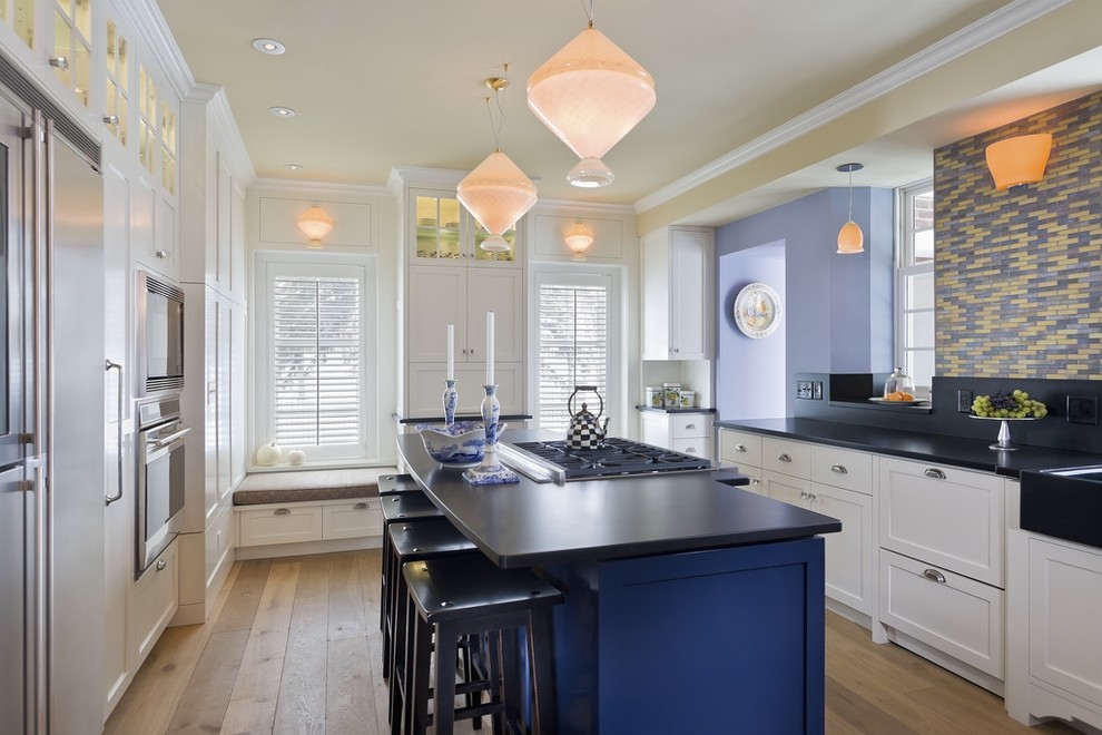 Inspiration for a traditional u-shaped kitchen in Other with a farmhouse sink, shaker cabinets, white cabinets, stainless steel appliances, medium hardwood floors and with island.